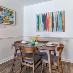 a dining table with chairs and a painting on the wall